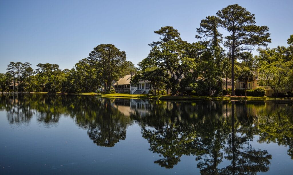 Scenic lake view of a Lowcountry plantation-style home surrounded by moss-draped oaks near Charleston